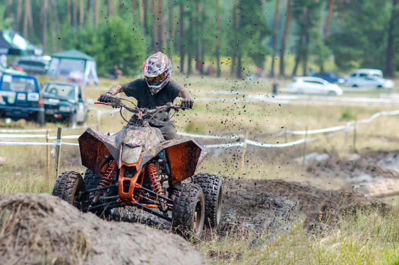 Person fährt mit einem Quad auf einer unbefestigten Rennbahn.