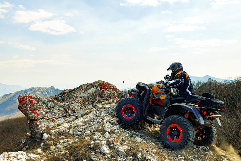 Eine Person fährt auf einer felsigen Landschaft Quad.