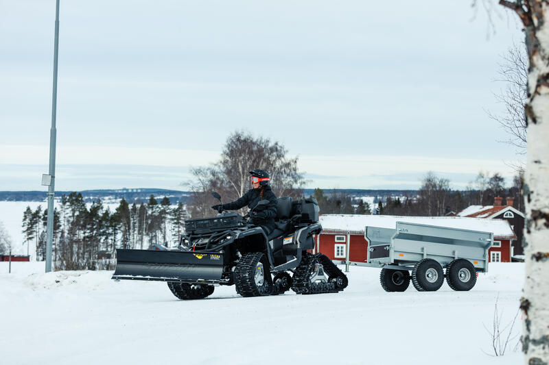 Winterdienst Eine Frau auf einem Quad mit Schneeschild fährt zum Winterdienst.